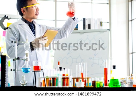 Asian man scientist with test tube making research in clinical laboratory.Science, chemistry, technology, biology and people concept