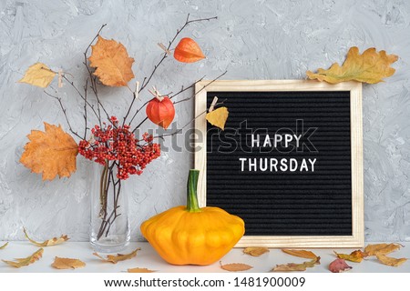 Happy Thursday text on black letter board and bouquet of branches with yellow leaves on clothespins in vase on table Template for postcard, greeting card Concept Hello autumn Thursday. Royalty-Free Stock Photo #1481900009