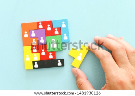 business concept image of tangram puzzle blocks with people icons over wooden table ,human resources and management concept