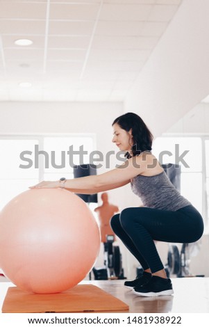 Attractive fit sporty woman working out in the gym, wearing sport watch. Fitness coach doing pilates exercise. Concept of active, sport and healthy living.