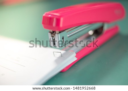 pink stapler does not pierce through many sheets of paper.shallow focus effect.