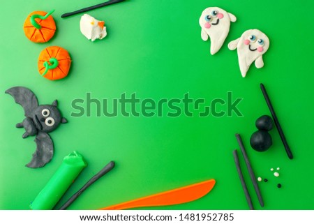 halloween concept. symbols and decorations made of polymer clay on green table flat lay top view, copy space, creative seasonal holiday DIY idea for kids