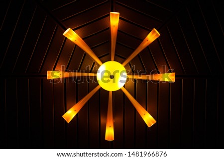 Glass chandelier with a yellow-orange glow on the ceiling