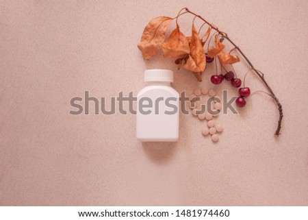
white jar with vitamins and pill-laden venus sign and a cherry tree branch with cherry berries and dry leaves