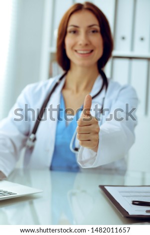Close up of female doctor thumbs up. Happy cheerful smiling brunette physician ready to examine patient. Medicine, healthcare and help concept