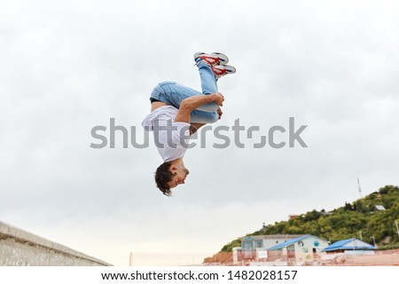 young man throwing a somersault outdoors, full length side view photo, copy space Royalty-Free Stock Photo #1482028157