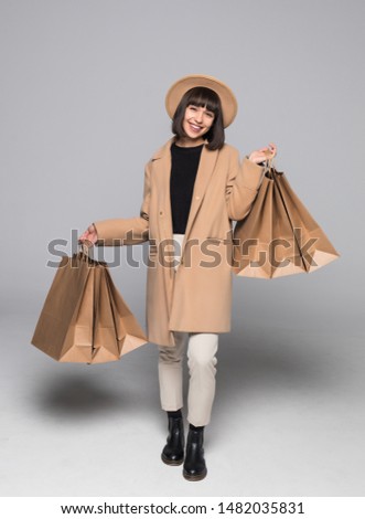 Woman wearing autumn overcoat holding shopping bag.