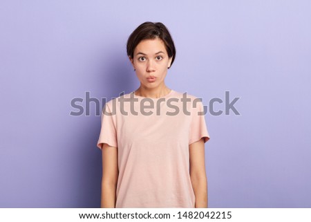 Closeup portrait of surprised young lady making moue with her lips isolated blue background, studio shot. facial expression.