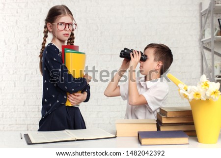Happy schoolchildren at a classroom looking through binoculars. Education.