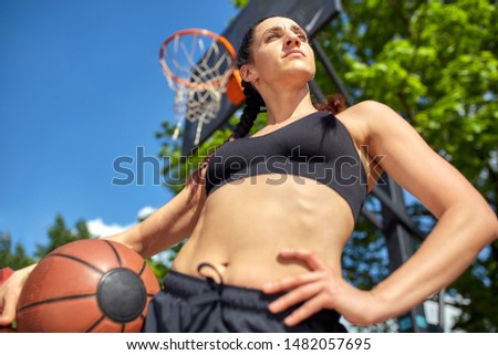 Beautiful, sporty latin girl with a basketball under the ring on a street basketball court. Sport motivation, healthy lifestyle, copy space, advertising banner.