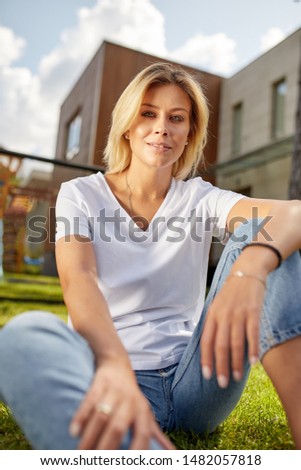 Beautiful young woman smiling at camera in a park outdoors. Outdoor recreation, happy life.