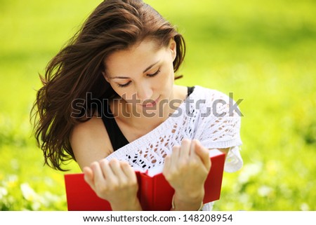 Image of young beautiful woman in summer park reading book