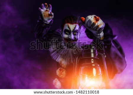A portrait of an angry crazy clown from a horror film with a lantern. Halloween, carnival.