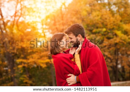 Loving couple. Beautiful young couple warped in blanket smiling and hugging  while standing  in autumn park Royalty-Free Stock Photo #1482113951