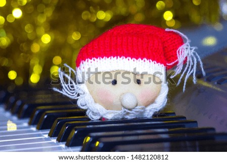 Toy Santa Claus on piano keys on blurred festive garland background