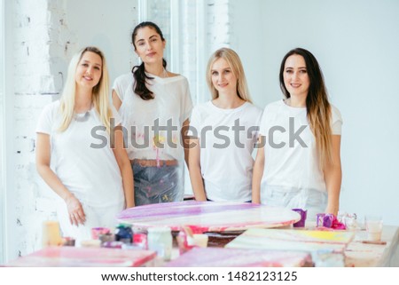Three female students with teacher finishing painting circle canvas picture together with pouring acrilic method creating fluid acrylic abstract in art therapy class. Art, design, creating concept. Royalty-Free Stock Photo #1482123125