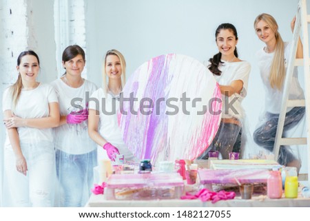 Four female students with teacher finishing painting circle canvas picture together with pouring acrilic method creating fluid acrylic abstract in art therapy class. Art, design, creating concept. Royalty-Free Stock Photo #1482127055