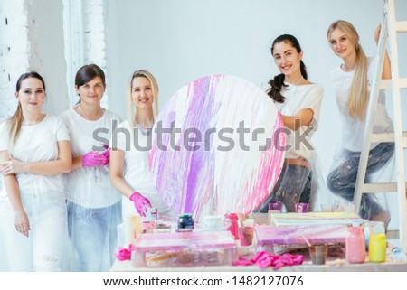 Four female students with teacher finishing painting circle canvas picture together with pouring acrilic method creating fluid acrylic abstract in art therapy class. Art, design, creating concept. Royalty-Free Stock Photo #1482127076