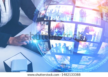 Woman using tablet on office table with double exposure of futuristic video streaming interface. Concept of hi tech and social media. Toned image