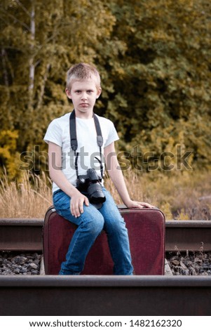 Boy with a camera on the railway in nature