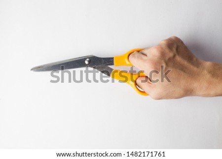 Hand using wear and tear scissors with yellow handle on white background , daily use peper work tool and easy to buy in stationery shop