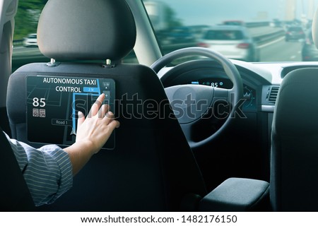 Passenger sitting in the backseat and  selects a route when autonomous taxi rides on the highway. Royalty-Free Stock Photo #1482176150