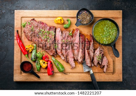 Modern design barbecue dry aged wagyu bavette de flanchet steak with chili and chimichurri sauce as top view on a wooden cutting board  Royalty-Free Stock Photo #1482221207