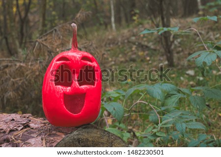 Funny and kind halloween pumpkin of pink color in the autumn forest. on a felled tree trunk