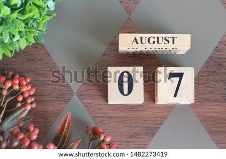 August 7. Date of August month. Number Cube with a flower and leaves on Diamond wood table for the background