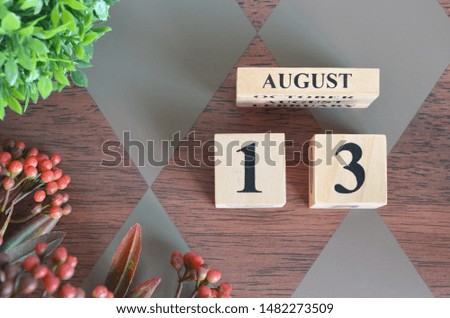 August 13. Date of August month. Number Cube with a flower and leaves on Diamond wood table for the background