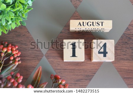 August 14. Date of August month. Number Cube with a flower and leaves on Diamond wood table for the background