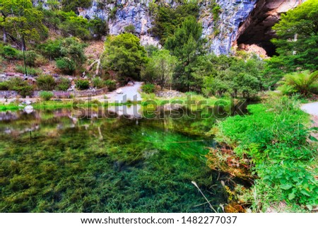 Blue Lake of Jenolan cave down from Charlotte arch with lush vegetation around and on lake bed with clean transparent fresh water reflecting grass and rocks.