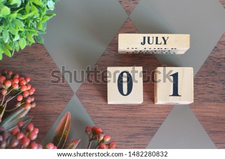July 1. Date of July month. Number Cube with a flower and leaves on Diamond wood table for the background
