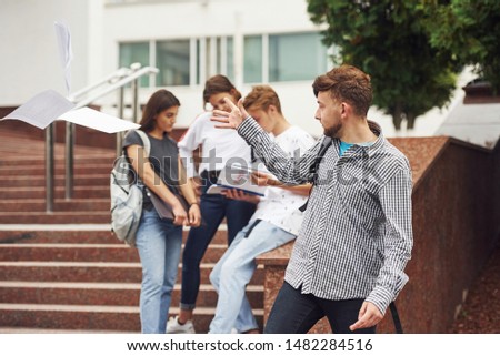 Positive guy. Group of young students in casual clothes near university at daytime.