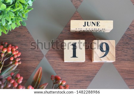 June 19. Date of June month. Number Cube with a flower and leaves on Diamond wood table for the background