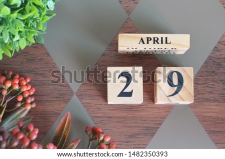 April 29. Date of April month. Number Cube with a flower and leaves on Diamond wood table for the background