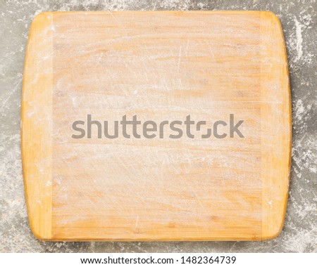 Wooden cutting board sprinkled with empty flour on a gray background. Copy space. Template for text or design. Top view