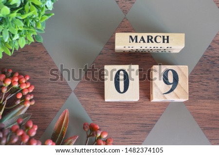 March 9. Date of March month. Number Cube with a flower and leaves on Diamond wood table for the background