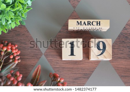 March 19. Date of March month. Number Cube with a flower and leaves on Diamond wood table for the background