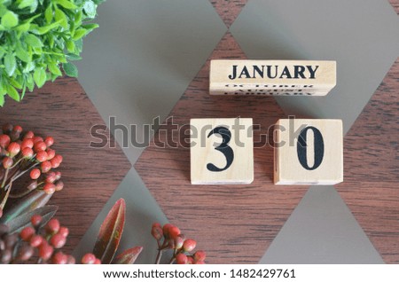 January 30. Date of January month. Number Cube with a flower and leaves on Diamond wood table for the background