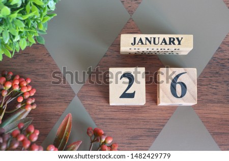 January 26. Date of January month. Number Cube with a flower and leaves on Diamond wood table for the background
