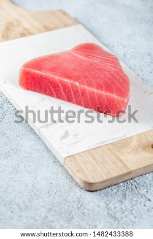 Raw tuna steak on white concrete background.