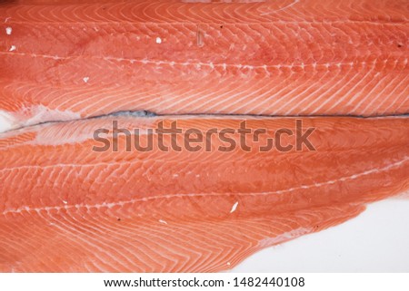 Detail closeup of salmon fish fillets on display at a fish market, freshly caught sea food on sale, uncooked piece ready for preparation in the kitchen 