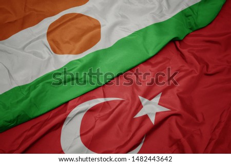 waving colorful flag of turkey and national flag of niger. macro