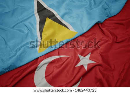 waving colorful flag of turkey and national flag of saint lucia. macro