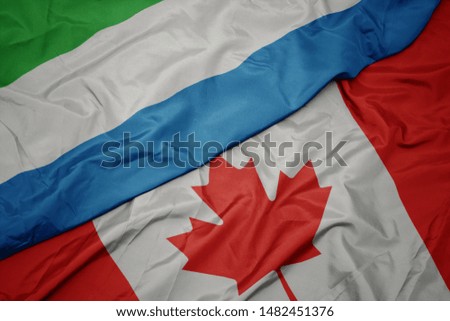 waving colorful flag of canada and national flag of sierra leone. macro