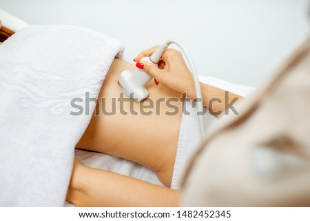 Female doctor performs ultrasound examination of a women's pelvic organs, close-up view Royalty-Free Stock Photo #1482452345