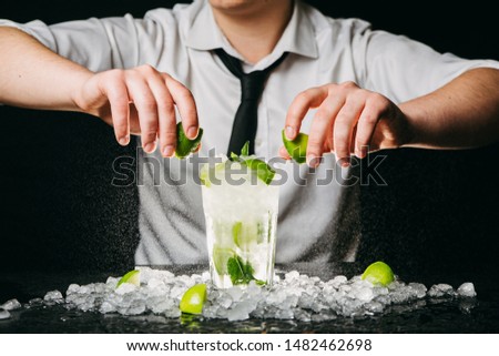 Close up of professional barman squeezing lime making Mojito cocktail