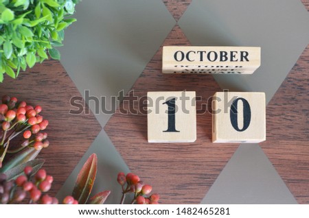 October 10. Date of October month. Number Cube with a flower and leaves on Diamond wood table for the background