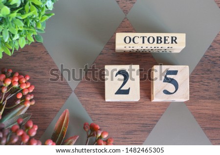 October 25. Date of October month. Number Cube with a flower and leaves on Diamond wood table for the background